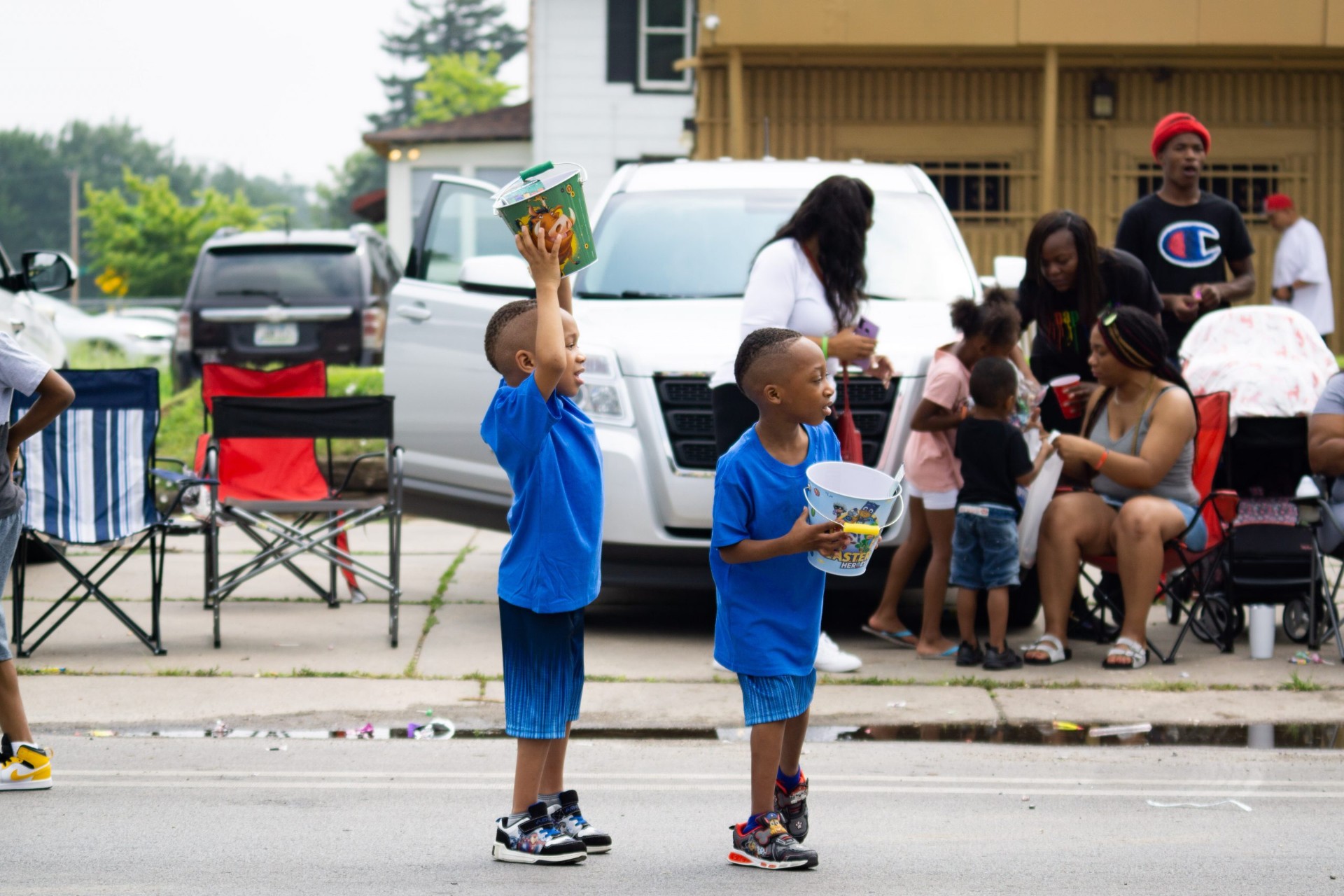Two boys in blue holding buckets waiting for candy