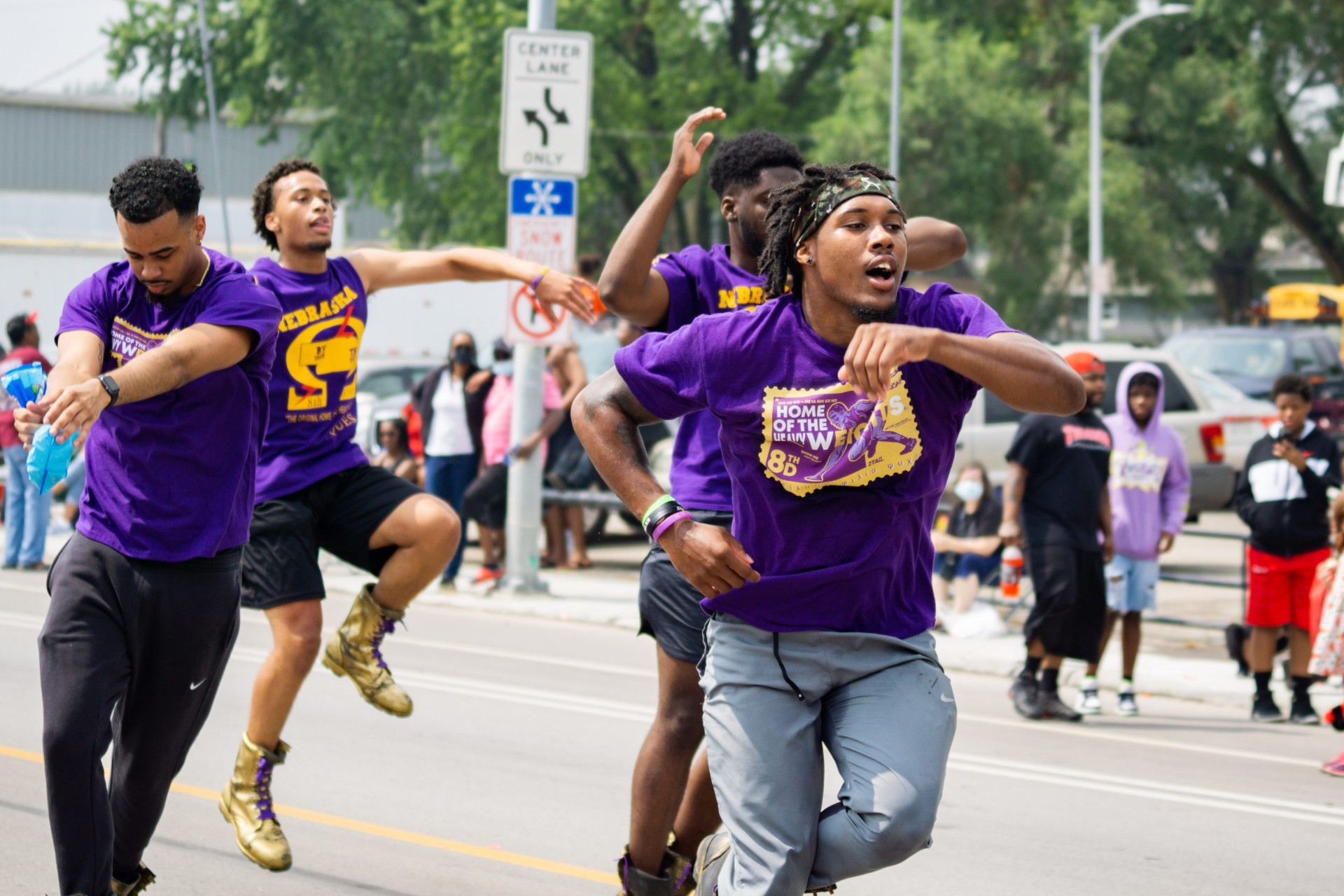 Steppers performing in purple shirts down the parade route